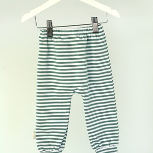 May include: Green and white striped baby leggings with a cuffed bottom.