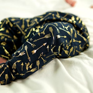 May include: A pair of navy blue baby leggings with a gold arrow print. The leggings are made of a soft, comfortable fabric and are perfect for everyday wear.