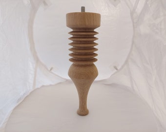 May include: A light-colored wooden furniture leg with a threaded top and a decorative, ribbed design. The leg has a turned, bulbous shape and a tapered foot. The overall design is classic and elegant.
