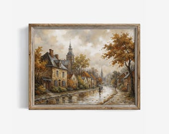 May include: A framed oil painting depicting a European village street scene during autumn. The artwork features stone buildings, a tall church steeple, and trees with golden-brown foliage lining a wet, reflective road under a cloudy sky.