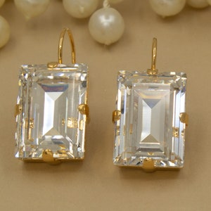 May include: A pair of gold earrings with large, clear, rectangular-shaped gemstones.