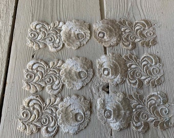 May include: Eight beige lace appliques with floral designs. Each applique features a large flower with smaller floral details around it.