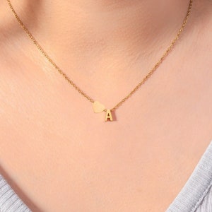 May include: A gold necklace with a small heart charm and a letter 'A' pendant.