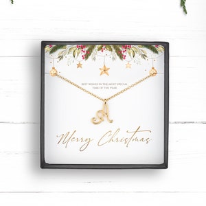 May include: A gold necklace with a cursive letter A charm in a gift box with a white background and a Christmas-themed design. The box has the text "Merry Christmas" on it.