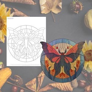 May include: A stained glass design of a butterfly with red, orange, yellow, blue, and black accents. The butterfly is in a circular frame with a grid pattern.