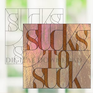 May include: A stained glass design with the words "SUCKS TO SUCK" in a bold, stylized font. The design features a mix of warm colors, including shades of pink, orange, and brown, with black outlines. A line drawing of the design is above the colored version.