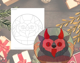 Puede incluir: Un diseño circular de vidriera con un diablo de dibujos animados con cuernos, ojos y lengua rojos. El diseño utiliza una combinación de colores negro y gris. También se muestra un dibujo lineal en blanco y negro del mismo diseño.