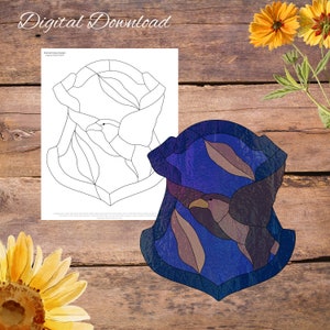 May include: A stained glass design of two birds flying in a blue and purple shield shape. The design is outlined in black and includes a printable pattern.