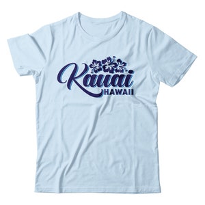 Könnte beinhalten: Hellblaues T-Shirt mit einem marineblauen Aufdruck des Wortes "Kauai" mit einem floralen Design und dem Text "Hawaii" darunter.