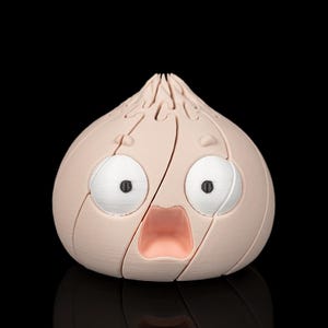 May include: A light pink, bulb-shaped object with a segmented surface resembling a garlic clove. It features two large, round white eyes with black pupils and a wide, open mouth with a light pink interior, creating a surprised facial expression.