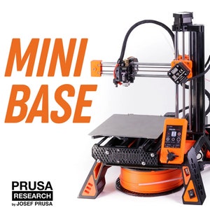 Puede incluir: Una impresora 3D negra y naranja con el texto "Original Prusa Mini" en la parte delantera. La impresora tiene una base negra y detalles en naranja. La impresora está sobre una superficie blanca.