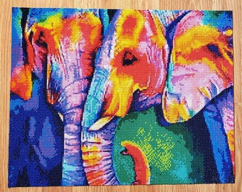 May include: A colorful diamond painting featuring three elephants. The artwork uses a mosaic technique with small, square resin rhinestones. The elephants are depicted in vibrant hues of blue, yellow, orange, and green, creating a striking visual effect.