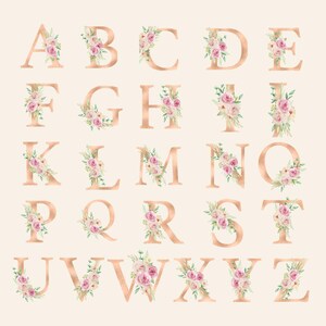 May include: A collection of rose gold alphabet letters, each adorned with a delicate arrangement of pink and white flowers and green leaves. The letters are displayed on a soft, cream-colored background, creating a romantic and elegant aesthetic.