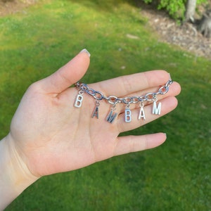 May include: A silver chain bracelet with letter charms spelling out the name "BAMBAM".