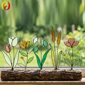 May include: A stained glass floral display with flowers and cattails in pink, yellow, green, and brown. The flowers are set in a natural wood base, suitable for a window or shelf, adding a touch of nature to any room.