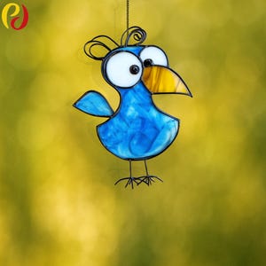 May include: A blue stained glass bird with large white eyes and a yellow beak. The bird is hanging from a wire and has a whimsical, cartoon-like design.