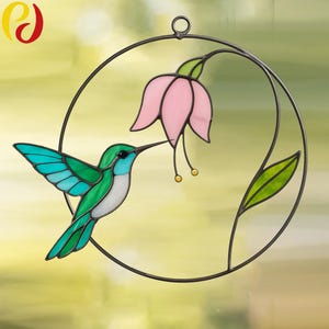 May include: A stained glass hummingbird with green and blue wings, perched on a circular metal frame, drinking nectar from a pink flower with a green stem and leaves.