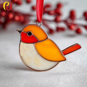 May include: A stained glass bird ornament with a red, orange, and white design. The bird has a red breast and a red ribbon for hanging. The ornament is approximately 4 inches in length.