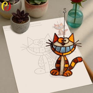 May include: A stained glass cat suncatcher with orange, brown, and blue accents. The cat has a wide grin and is hanging from a metal chain. A drawing of the cat is on a piece of paper with a pencil.