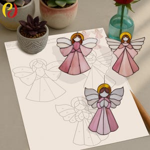 Puede incluir: Tres adornos de ángeles de vidrieras en tonos rosa y blanco, con halos dorados. Los ángeles se exhiben sobre una superficie clara con un dibujo de un ángel. Una rosa roja en un pequeño jarrón verde está en el fondo.