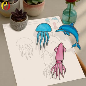 Peut inclure: Un projet artisanal avec des créatures marines en vitrail : une méduse bleue, un calmar rose et un dauphin bleu. Les créatures sont placées sur un papier avec un motif de peinture par numéros partiellement terminé. De petites plantes en pot et un vase avec une rose rouge sont en arrière-plan.