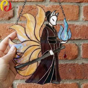 May include: Stained glass artwork depicting a kitsune figure with nine tails, holding a sword and a blue flame. The figure is in a kimono with a fox mask. The artwork is suspended by a chain.