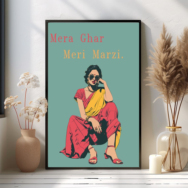 May include: A woman wearing a yellow and red sari sits with her legs crossed, wearing sunglasses and looking to the side. The background is a teal blue color and the text "Mera Ghar Meri Marzi." is written in orange and white.