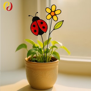 May include: A potted plant with a decorative ladybug and flower stake. The ladybug is red with black spots and a black head. The flower is yellow with an orange center. The pot is beige and has a textured design.