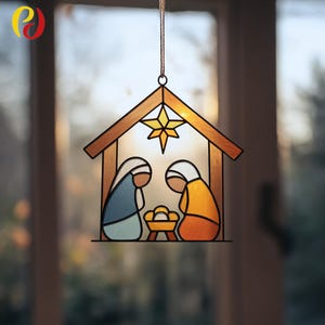 May include: Stained glass Nativity scene with a wooden frame, featuring Mary and Joseph, a manger, and a star. The figures are in blue and yellow, with a gold star at the top. The scene is hanging by a string.