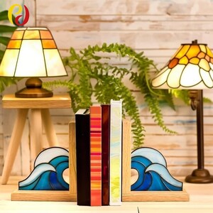 May include: Wooden bookends with a stained glass wave design in blue and white, holding books. Two Tiffany-style lamps with orange and yellow shades flank the books. The lamps are on wooden stands. The scene is set against a wooden backdrop.
