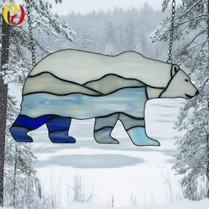 May include: Stained glass polar bear hanging decoration. The bear is white, blue, and gray, with a landscape design. It hangs from a chain. The background is a snowy forest.