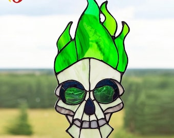 Puede incluir: Calavera de vidriera con llamas verdes. La calavera tiene una base blanca con detalles en negro y verde. Las llamas son de color verde vibrante. Esta pieza decorativa está diseñada para colgarse en una ventana.