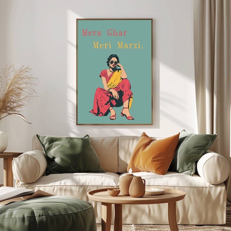 May include: A framed poster with a teal background featuring a woman wearing a red and yellow sari and sunglasses. The text on the poster reads "Mera Ghar Meri Marzi."
