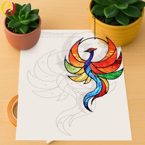 Peut inclure: Un phénix en verre coloré avec des couleurs arc-en-ciel suspendu à une chaîne noire. Le phénix est sur une feuille de papier blanche avec un contour numéroté du phénix.