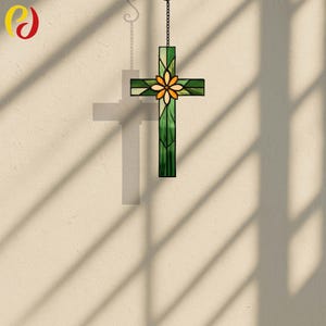 May include: A stained glass cross with a green and yellow floral design. The cross is suspended from a chain and features a central flower motif. The cross is made of various shades of green and yellow glass, creating a vibrant and decorative piece.