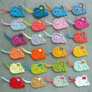 Könnte beinhalten: Eine Sammlung farbenfroher, gehäkelter Mäuse-Ornamente. Jede Maus hat eine andere Farbe, darunter Blau, Rosa, Orange und Grün, mit kontrastierenden Schwanz- und Ohrendetails. Diese handgefertigten Artikel sind wahrscheinlich für Dekorations- oder Bastelprojekte gedacht.