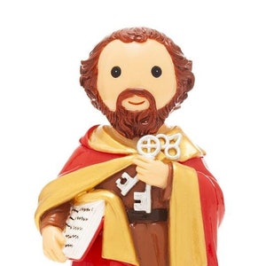May include: A small figurine of Saint Peter, a religious figure, holding a key and a book. He is wearing a red and gold robe and has a brown beard.