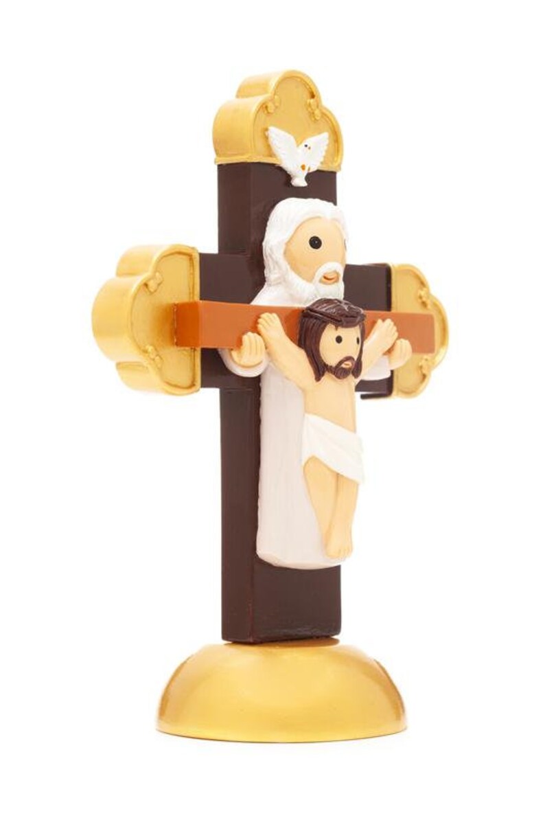 May include: A brown wooden cross with a gold base. A white figure of Jesus is on the cross with a dove above. A white figure of God is behind Jesus with his arms around Jesus.