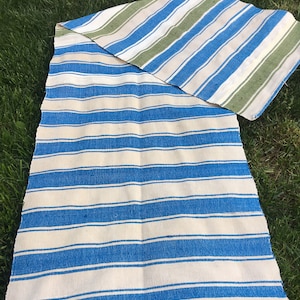 Puede incluir: Una manta de rayas con rayas azules y blancas en un lado y rayas verdes, blancas y azules en el otro.