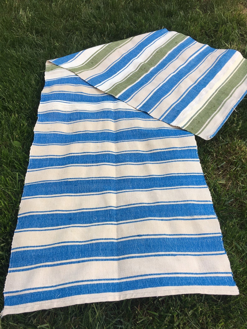 Puede incluir: Una manta de rayas con rayas azules y blancas en un lado y rayas verdes, blancas y azules en el otro.