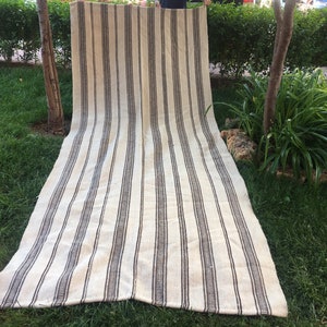 May include: A long, striped rug with white and brown stripes. The rug is made of a natural fibre and has a rustic look.