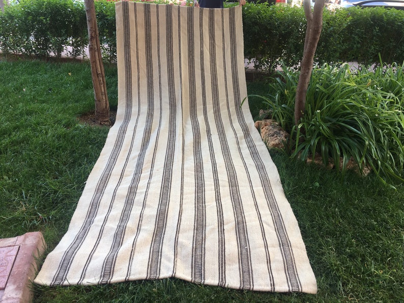 May include: A long, striped rug with white and brown stripes. The rug is made of a natural fibre and has a rustic look.