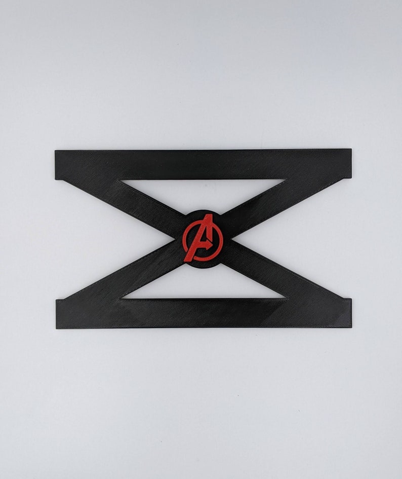 May include: Black plastic stand with a red and white Avengers logo in the center. The stand is shaped like an X.