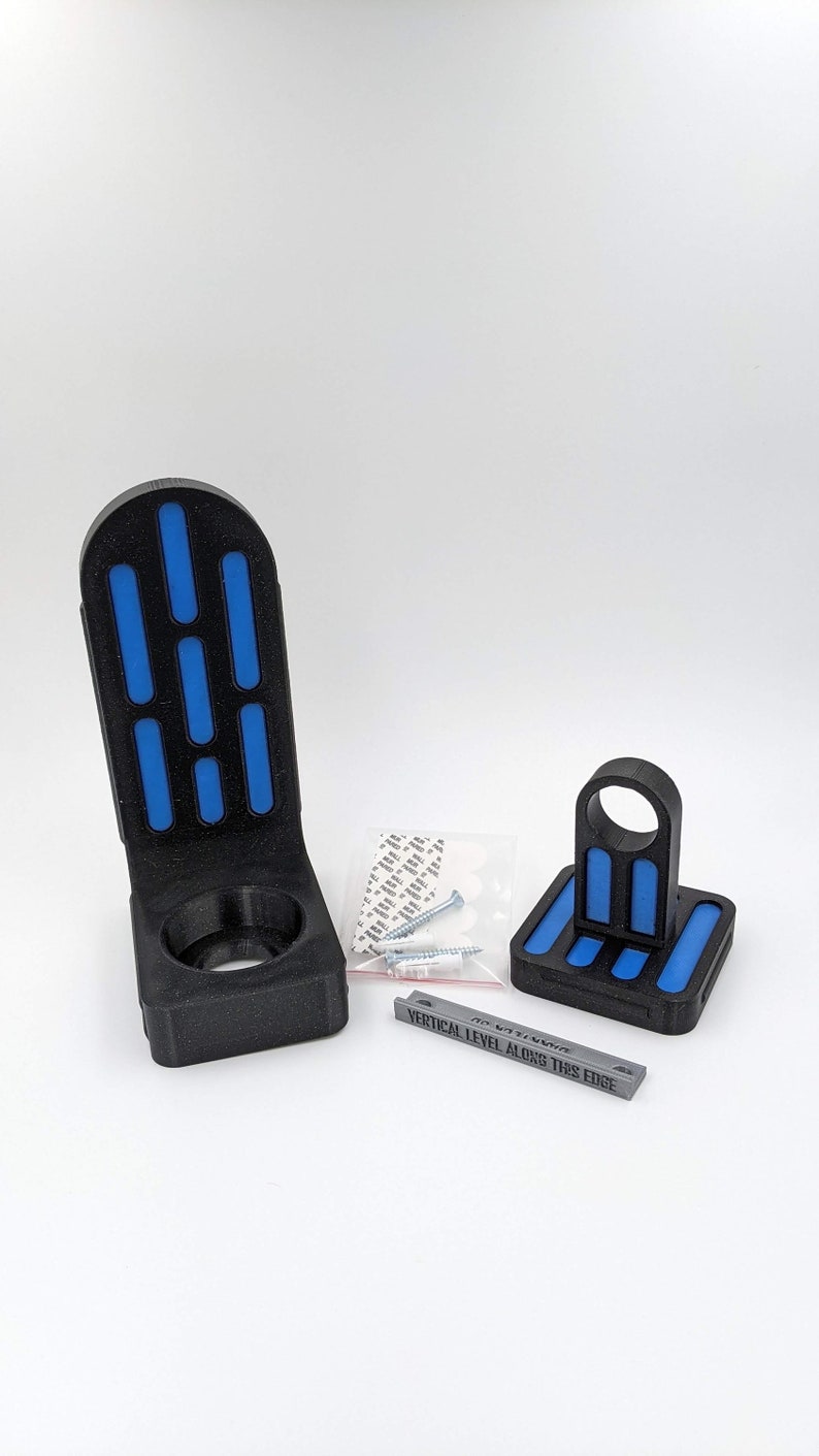 以下が含まれることがあります： ライトセーバー用の円形開口部を持つ、黒と青の3Dプリントされた壁掛け。マウントにはレベルインジケーターが付属しており、取り付け用のネジと粘着ストリップが付属しています。  "VERTICAL LEVEL ALONG THIS EDGE"はレベルインジケーターに印刷されています。