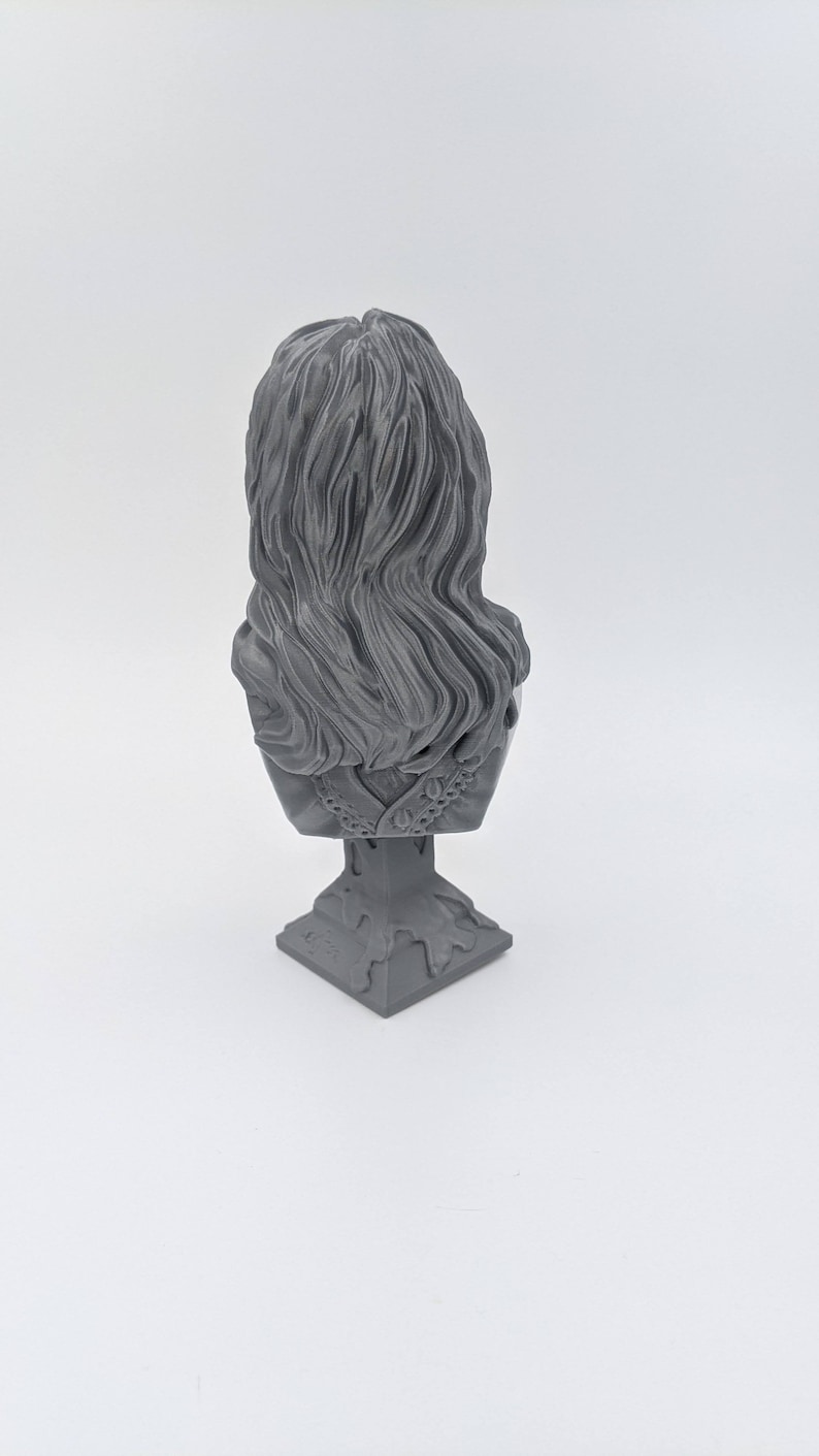 May include: A gray 3D printed bust of a person with long hair, the bust is on a square base.