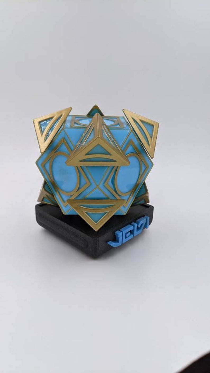 May include: A blue and gold geometric sculpture with a black base. The base has the word "JEIZI" printed in blue.