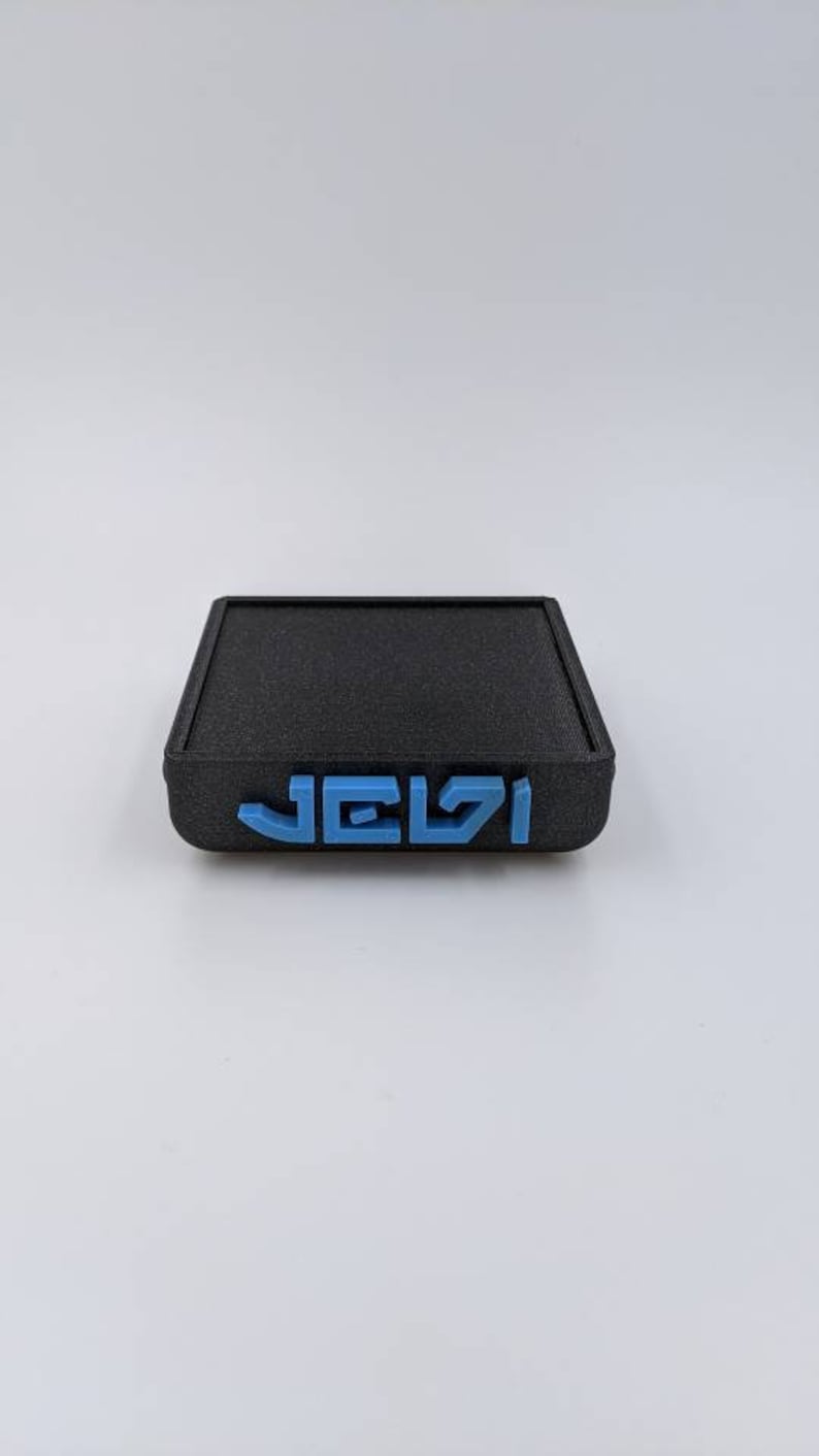 May include: A black square-shaped box with the word "JELZI" printed in blue on the front.