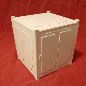 May include: A white, cube-shaped box with two doors on the front. The box has a textured surface and is made of a sturdy material.