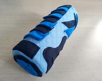 May include: A blue and navy blue fabric cylinder pillow with a quilted design. The pillow is made of different shapes and sizes of fabric.