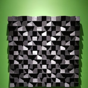 Può includere: Un'opera d'arte murale geometrica in bianco e nero realizzata in legno. Il pezzo è composto da una serie di quadrati e triangoli che creano un motivo ondulato.